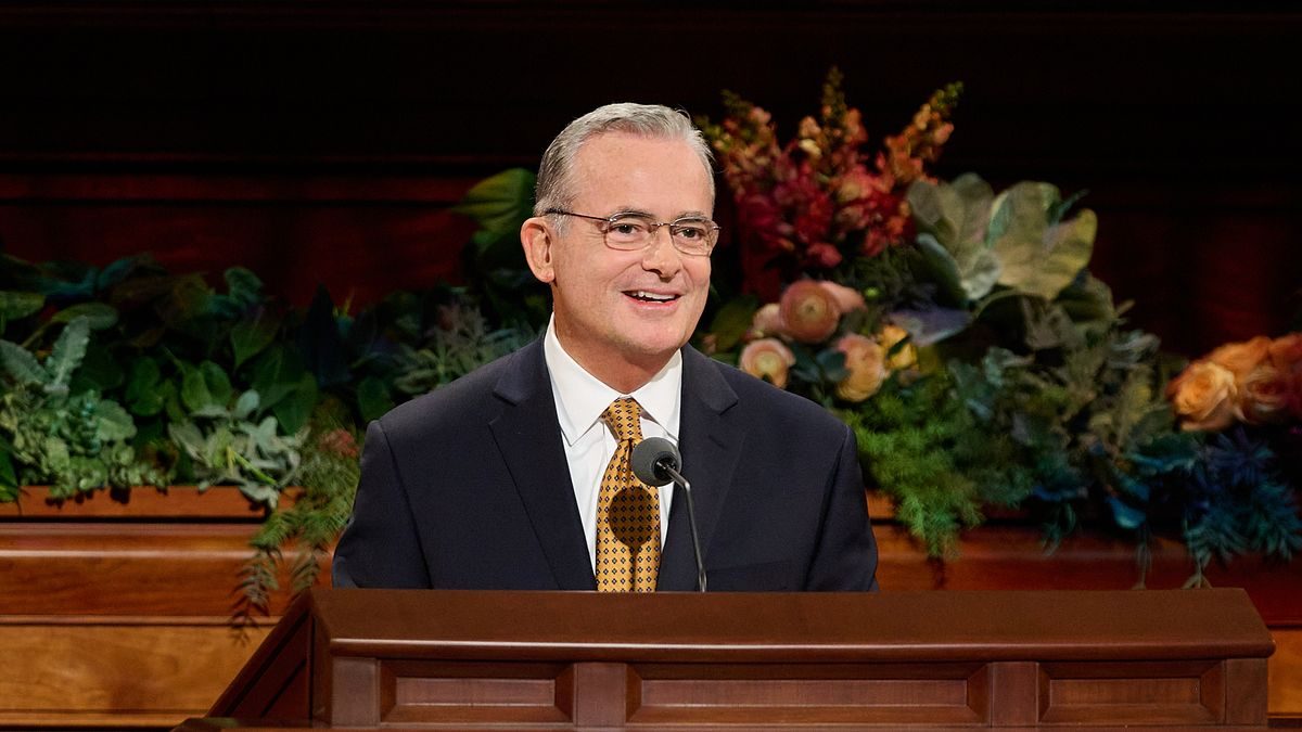 Elder Patrick Kearon smiling at the general conference pulpit