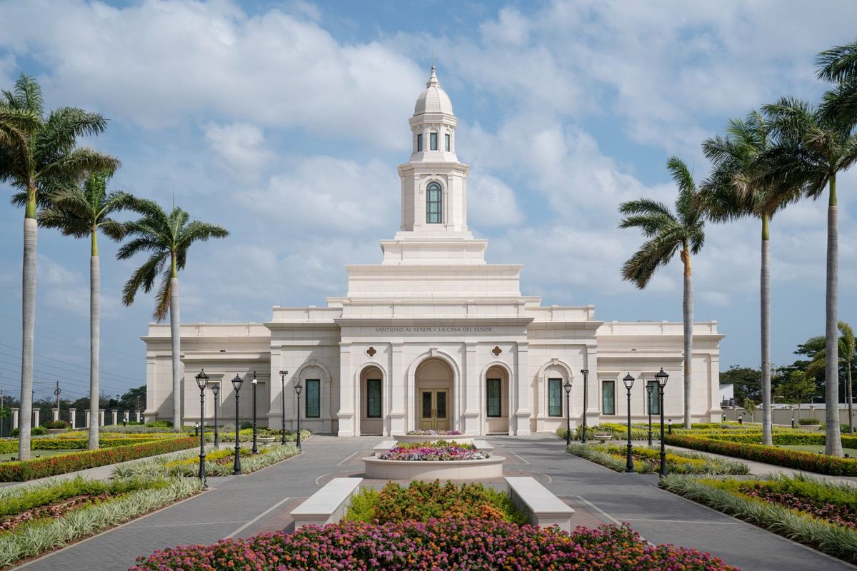 Exterior of the Managua Nicaragua Temple framed by palm trees and flower beds