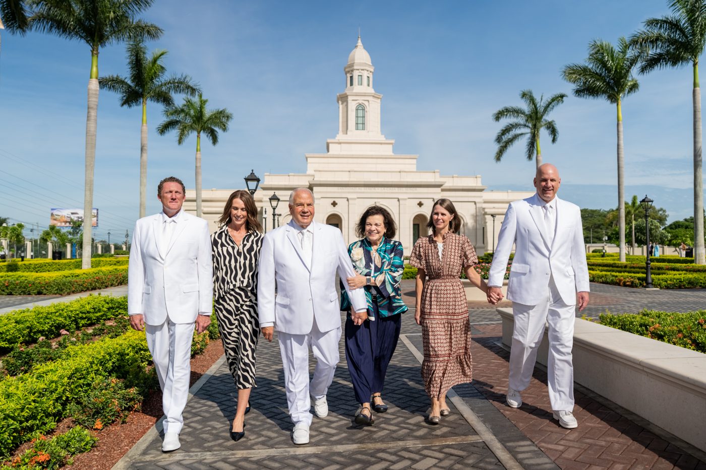 Elder and Sister Rasband walking with other leaders and their wives on the palm-lined path in front of the Managua Nicaragua Temple