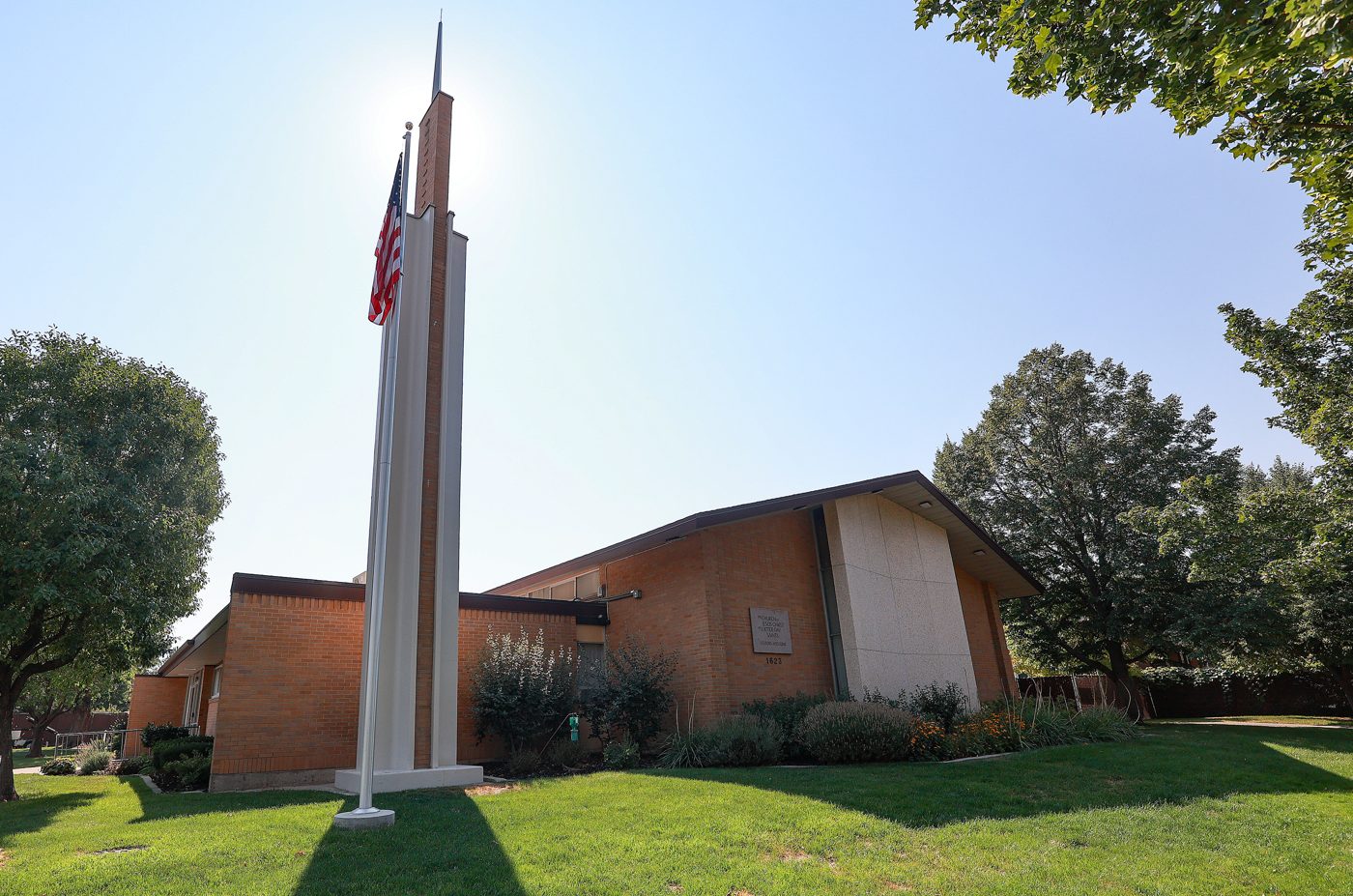 A Latter-day Saint meetinghouse with its steeple against a blue sky
