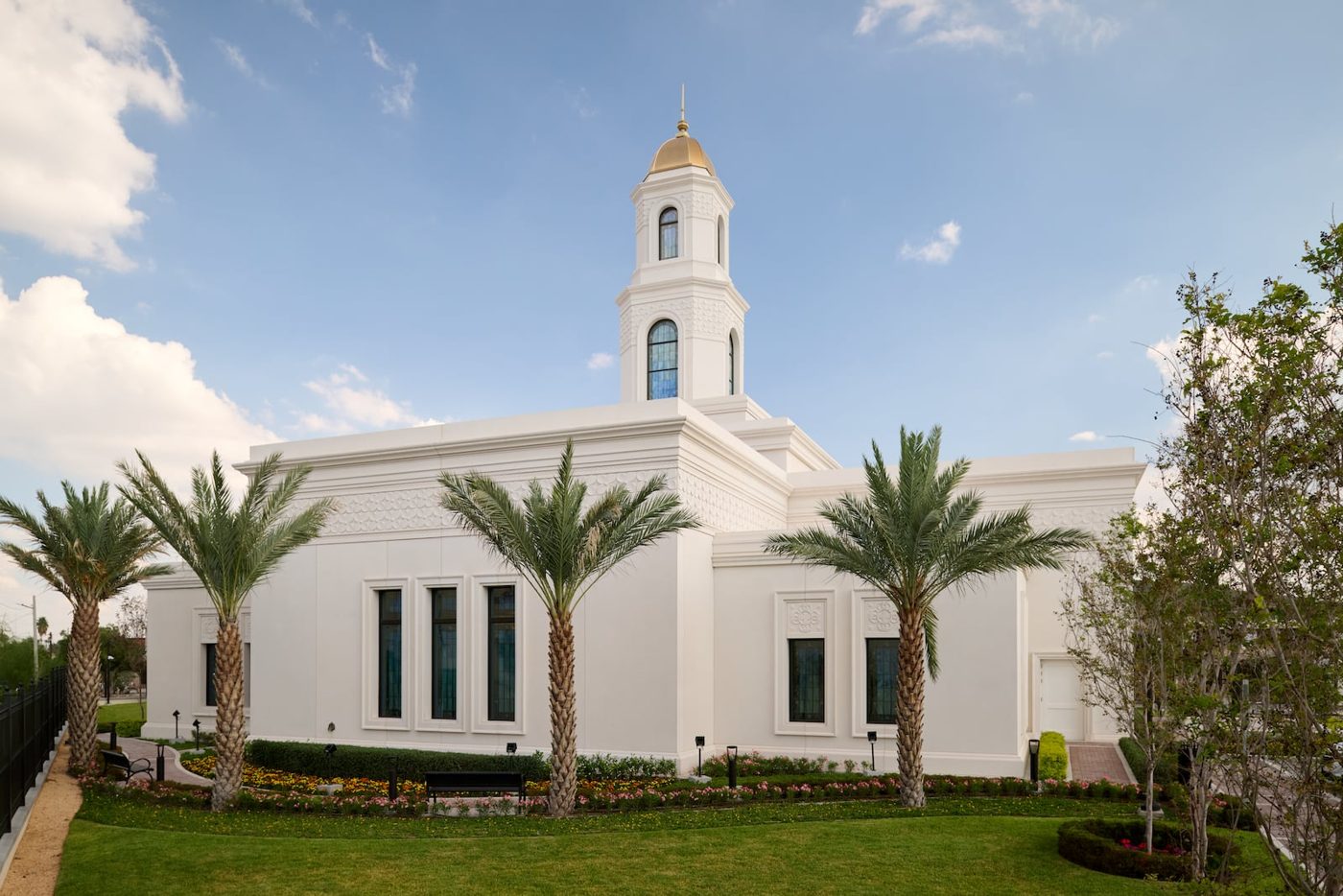 The white Torreón Mexico Temple with its gold-domed tower and palm trees under a blue sky